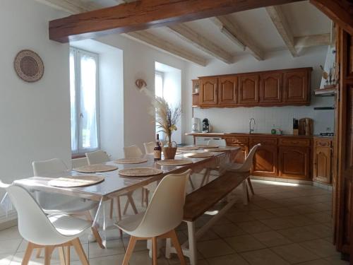 une cuisine avec une table et des chaises dans une pièce dans l'établissement Maison à la campagne avec piscine 12 pers, à Genouillé