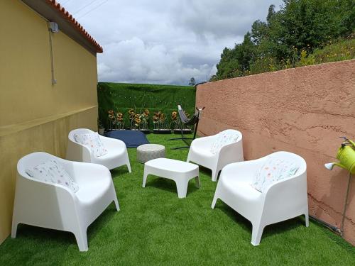 a group of white chairs sitting on the grass at Casa Davó Cinda in Paredes de Coura