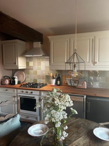 - une cuisine avec des placards blancs et une table fleurie dans l'établissement Maison de charme avec jardin, à Semur-en-Auxois