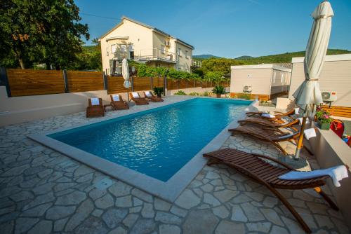 een zwembad met ligstoelen en een parasol bij Holiday Home Trend in Donji Zagon