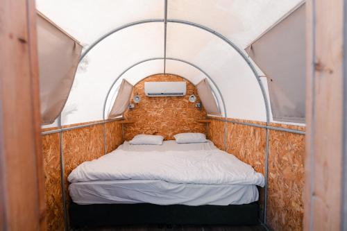 a bed in a tent with an arched ceiling at Badolina Ein Gedi Glamping in Ein Gedi