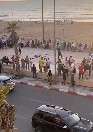 a group of people standing on a sidewalk near the beach at Appartement mehdia en face de la plage in Kenitra