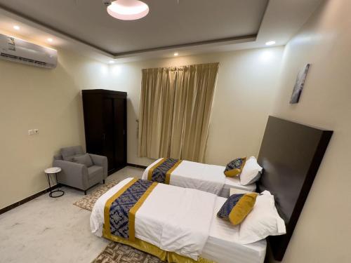 a hotel room with two beds and a chair at Tamyoz Aqama for Serviced Apartments in Hail