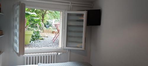 a window in a room with a view of a garden at Chambre indépendante chez l'habitant avec salle de bain privée in Alençon