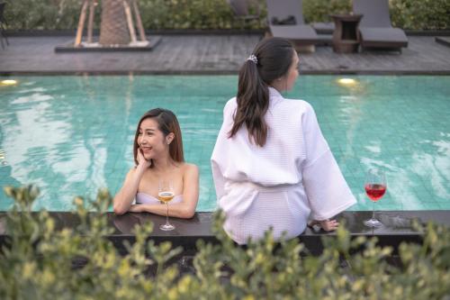 a woman talking on a cell phone next to a pool at SeeView Resort (ซีวิว รีสอร์ต) in Ban Pak Nam