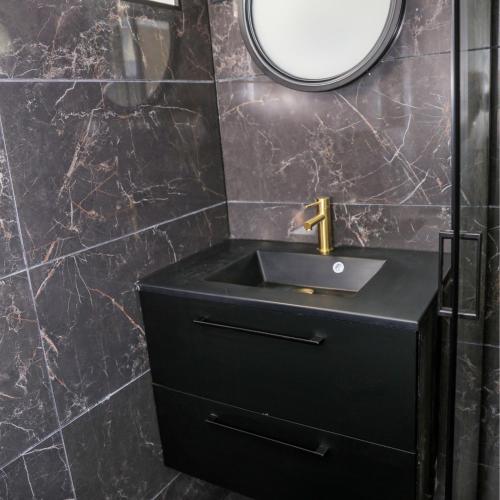 une salle de bain avec un lavabo noir et un miroir dans l'établissement Cinéma Privé-Compiègne - Sitivia, à Margny-lès-Compiègne