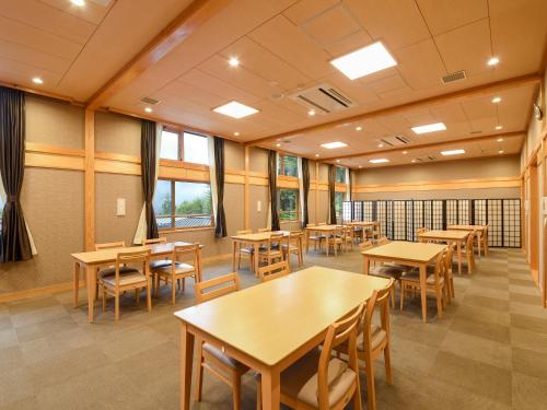 a classroom with tables and chairs and windows at はなぞの温泉 花圃の里 in Oshite