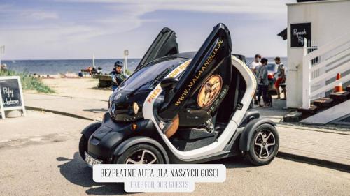 a small car parked next to the beach at Mała Anglia Deluxe Rooms & SPA in Sopot