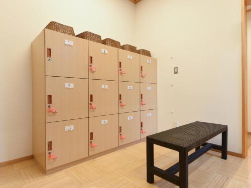 a locker room with a bench and a wall of lockers at はなぞの温泉 花圃の里 in Oshite