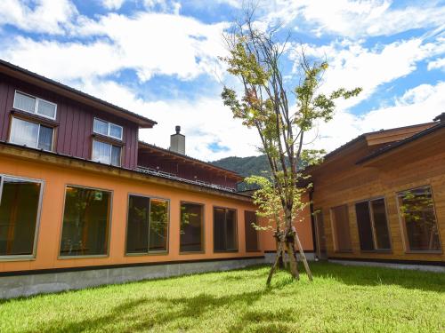 a tree in a yard next to a building at はなぞの温泉 花圃の里 in Oshite