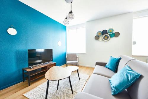 un salon avec un canapé et un mur bleu dans l'établissement BM-1 Appartement au 1er étage - F2 - 1 à 4 pers, à Mulhouse
