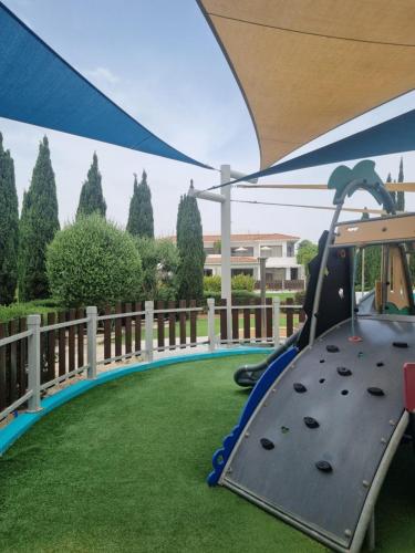 a playground with a swing set and grass at Atlantis Gardens in Mazotos
