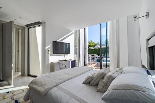 - une chambre blanche avec un grand lit et une télévision dans l'établissement Villa IRIS, à Ramatuelle