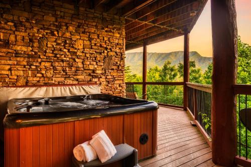 a jacuzzi tub on a deck with a view at Great Alpine - 4 KingSuites- December Deals-Views-Hot Tub-FirePit-GameRm in Gatlinburg