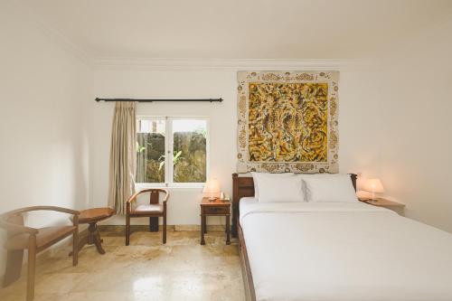 ein Schlafzimmer mit einem Bett, einem Stuhl und einem Fenster in der Unterkunft Sari Bunga Hotel - Legian, walking distance to Legian Beach in Legian