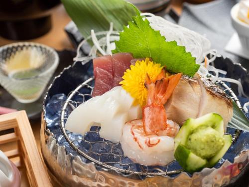 a plate of food with sushi and vegetables on a table at はなぞの温泉 花圃の里 in Oshite