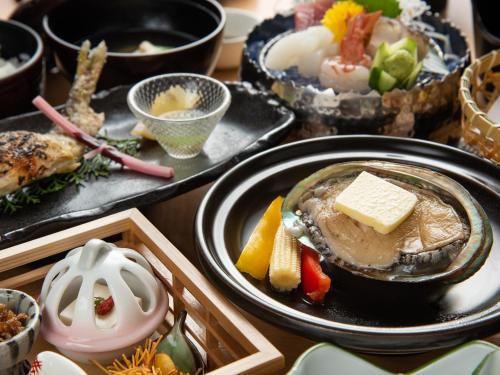 a table topped with plates of food with different foods at はなぞの温泉 花圃の里 in Oshite