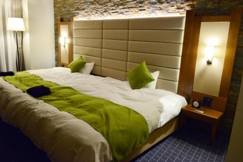 a bedroom with a large bed with green pillows at Satsuma Resort Hotel in Satsuma