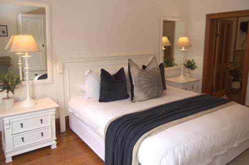 a bedroom with a white bed with pillows on it at Killassy House in Graaff-Reinet