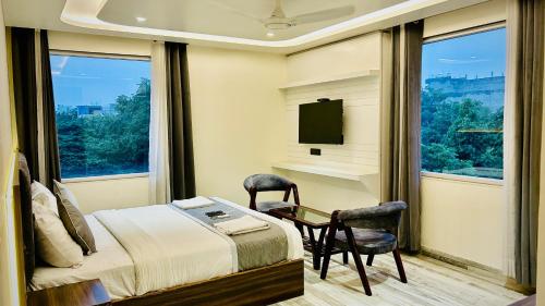 a bedroom with a bed and a table and two chairs at Raksha Suites & Banquet Greater Noida in Greater Noida
