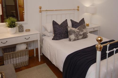 a bedroom with a white bed with pillows on it at Killassy House in Graaff-Reinet