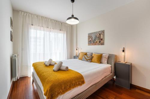 a bedroom with a large bed with a yellow blanket at GuestReady - Teddy Jazz in Porto