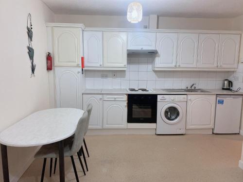 a kitchen with white cabinets and a table and a dishwasher at Maynooth in Maynooth