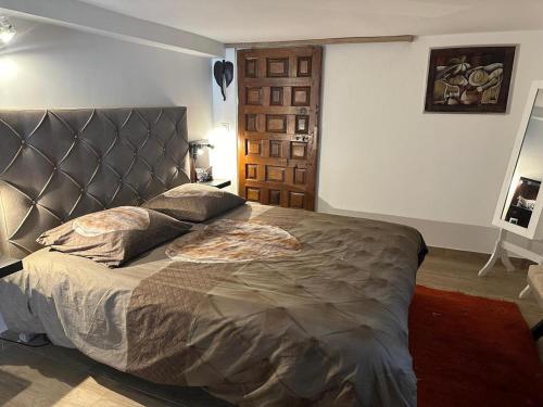 - une chambre avec un grand lit et une tête de lit en cuir dans l'établissement Maison Changrila, à Chennevières-sur-Marne