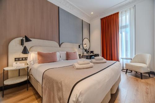 a hotel room with a large bed and a chair at Soho Boutique Turia in Valencia