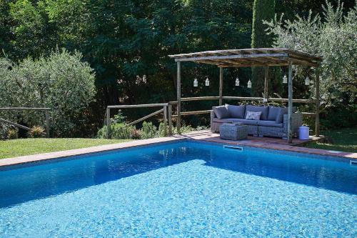 a swimming pool with a gazebo and a couch next to a pool at Il Vecchio Milipano in Montepulciano