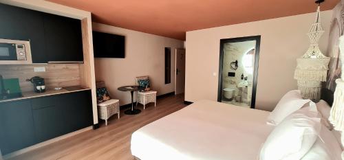 a bedroom with a large white bed and a bathroom at Hotel Suites Moma Centro in Villanueva de la Serena