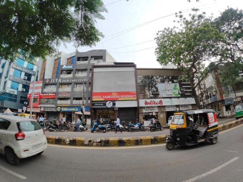 a busy city street with cars and motorcycles in front of buildings at Hotel Samruddhi Residency in Jamnagar