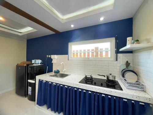 a kitchen with a stove and a blue wall at Aso Living in Bantul