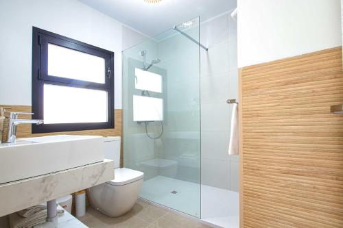 a bathroom with a toilet and a glass shower at Linda Vista Beach Apartment in Marbella