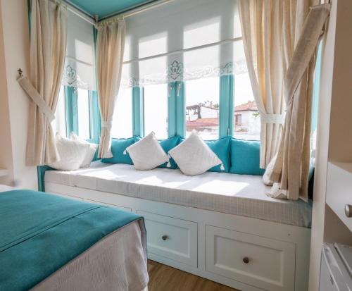 a window seat in a bedroom with blue curtains at Kairos Hotel in Siğacık