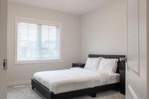 a bedroom with a bed with white sheets and a window at 10 Minutes From The Falls in Thorold