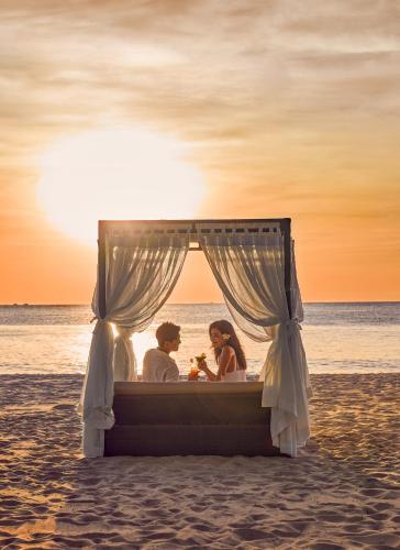 a couple sitting in a bed on the beach at Melia Vinpearl Phu Quoc in Phu Quoc