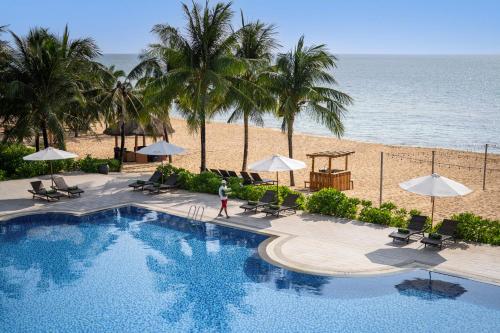 a person walking by a swimming pool next to the beach at Melia Vinpearl Phu Quoc in Phu Quoc