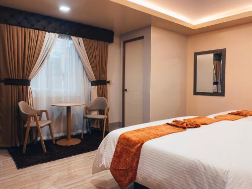 レガスピにあるEmmie Hotelのベッドとテーブルと椅子のあるホテルの部屋