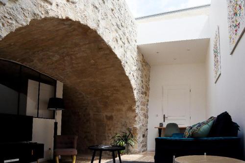 a living room with a stone wall and a blue couch at Gîte Sainte Marguerite-La Nonette in Senlis