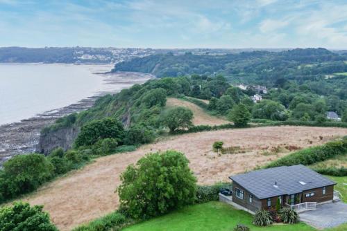 a house on a hill next to a body of water at Shearwater 30 - 2 Bedroom Lodge - Summerhill in Amroth