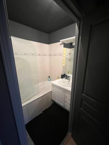 La salle de bains est pourvue d'une baignoire blanche, d'un lavabo et d'une baignoire. dans l'établissement Appartement Cosy Le Chesnay, à Le Chesnay