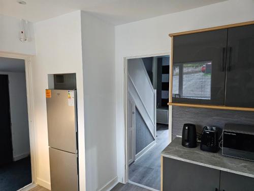 a small kitchen with a refrigerator and a staircase at Bridgepay Modern 4 bedroom House in Cumbria - Whitehaven - Free Parking in Whitehaven