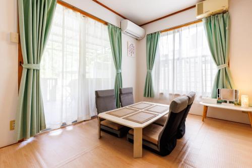 a living room with a table and chairs and large windows at 新規オープン サウナ BBQ ジャグジー付き 最大9名 無料駐車場4台 ビーチまで車で5分 SKY House in Uruma