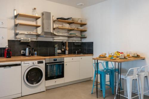 une cuisine avec un lave-linge et une table avec des tabourets dans l'établissement L'industriel - Hypercentre-Quartier Saint François, au Havre
