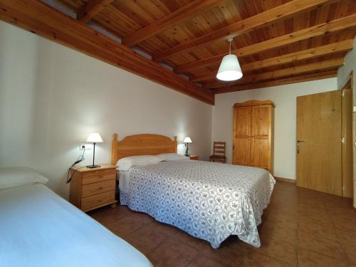 a bedroom with two beds and a wooden ceiling at Casa Rural el Rincón in Perarrua