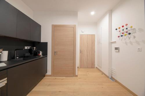 - une cuisine avec comptoirs en noir et blanc et une porte en bois dans l'établissement Le Petit Vasselot, à Rennes