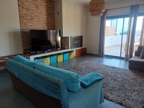 a living room with a blue couch and a television at Casa da Praia em Porto Côvo in Porto Covo