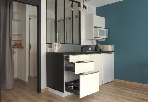 une cuisine avec des armoires blanches et un micro-ondes dans l'établissement Kings and Queens - Studio rénové - Notre-Dame, au Havre