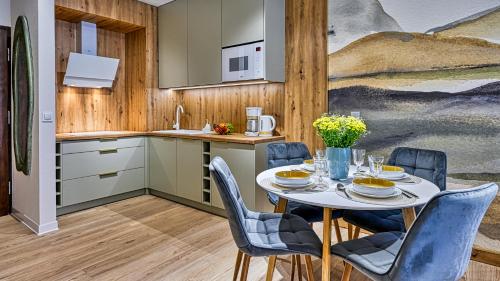a kitchen with a table and chairs and a kitchen with a painting at Źródło Izery przy gondoli VIP Sauna, Siłownia, Bawialnia by Royal Aparts in Świeradów-Zdrój